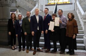 Council Member Mark Jeffreys, center with white tie, with Jewish community members after the City Council approved his resolution to adopt the IHRA antisemitism definition. (Courtesy AJC)