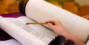 hand with a yad pointing at a torah