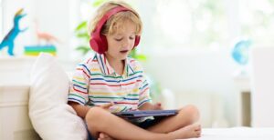 child with headphones on a tablet.
