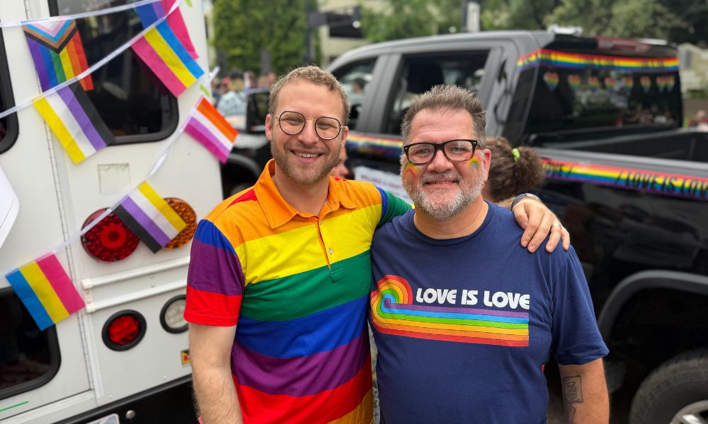 Two men with their arms over each others shoulders smiling at Cincinnati Pride Parade